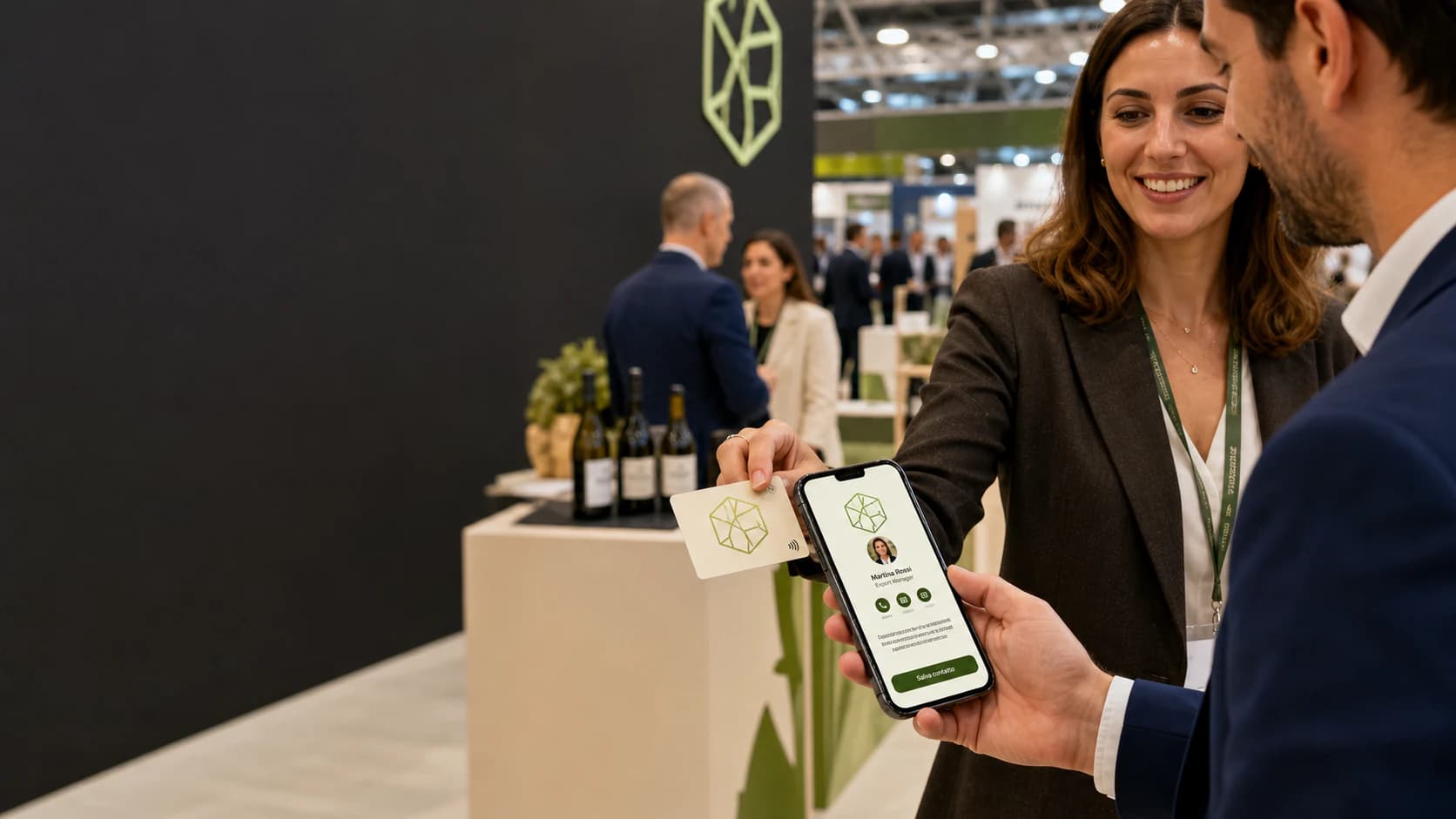 Espositrice consegna una card NFC con logo a un visitatore con il profilo acceso sul telefono